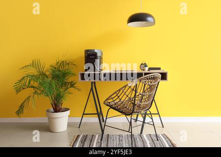 Interno dell'ufficio con postazione di lavoro, centrale elettrica portatile e palma Foto Stock