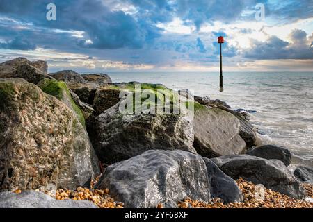 Un Sea Defence Post con rocce protettive in primo piano a Hythe Beach, Kent Foto Stock