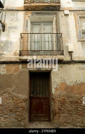 Un primo piano di un antico balcone con ringhiere ornate su un vecchio edificio urbano con pareti in angoscia Foto Stock