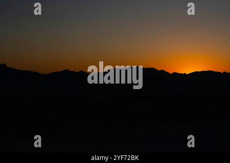 Retroilluminazione dall'arancio del tramonto dietro la sagoma delle Andres Mountains nel White Sands National Park Foto Stock