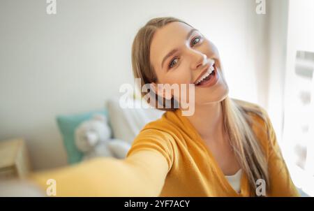 Teen girl sorridente in una stanza accogliente e soleggiata durante il pomeriggio Foto Stock