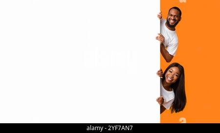 Coppia nera che sbirciava il cartellone pubblicitario bianco in studio Foto Stock