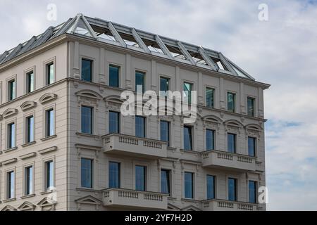 Edificio elegante con elementi architettonici neoclassici e grandi finestre, caratterizzato da balconi e dettagli ornati sotto un cielo nuvoloso Foto Stock