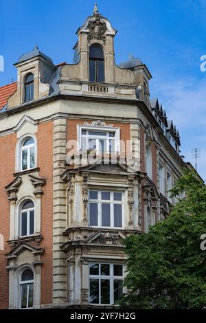 Facciata di un edificio storico europeo con intricati dettagli architettonici, finestre d'epoca e un design d'angolo splendidamente conservato sotto un cielo blu Foto Stock