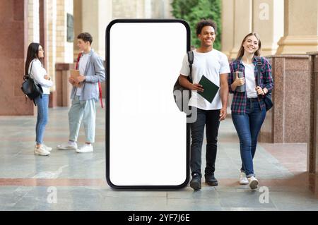 Studenti che camminano in un corridoio universitario con un grande schermo vuoto per smartphone Foto Stock