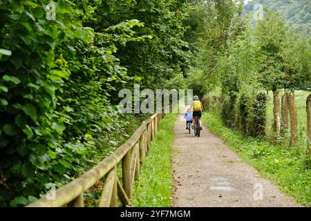 Madre e bambino pedalano lungo una strada di campagna Foto Stock