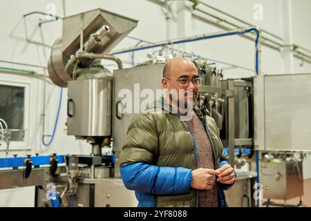 Il proprietario della fabbrica di birra cammina tra i serbatoi industriali dell'impianto di fermentazione Foto Stock