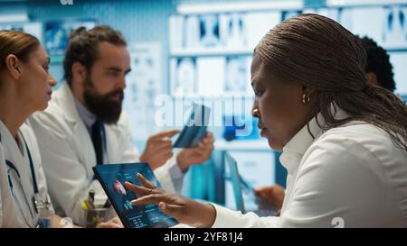 Radiologi diversi team che esaminano i raggi X per discutere l'assistenza al paziente in una struttura. Team di specialisti sanitari qualificati che lavorano insieme per fornire una diagnosi accurata e piani di trattamento. Telecamera B.. Foto Stock