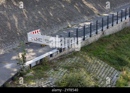 Pista ciclabile chiusa vicino al fiume bloccata a causa di inondazioni dopo forti piogge. Le barriere di sicurezza impediscono l'accesso, evidenziando il controllo delle alluvioni urbane Foto Stock