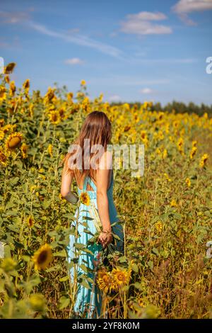 Donna in abito estivo che abbraccia la bellezza dei girasoli e la speranza per la pace Foto Stock