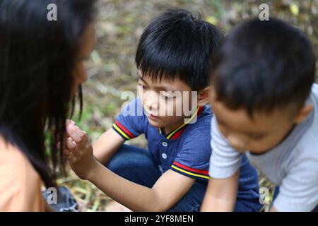 Due bambini si impegnano in un'interazione giocosa in un ambiente naturale all'aperto, condividendo momenti gioiosi che mostrano amicizia e esplorazioni dell'infanzia Foto Stock