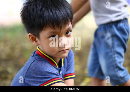 Un bambino esprime la propria serietà mentre si gode un momento all'aperto. Catturando l'essenza dell'infanzia, questa immagine enfatizza l'innocenza e il cu Foto Stock