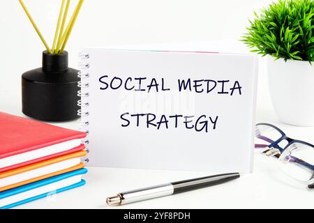 Il concetto di business dell'informazione. Il testo DELLA STRATEGIA SUI SOCIAL MEDIA è scritto su un foglio vuoto di blocco note. Foto Stock