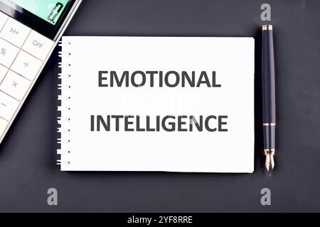 Concetto di business. La frase, il testo e le parole di INTELLIGENZA EMOTIVA sono scritte in un quaderno su uno sfondo blu scuro. Foto Stock