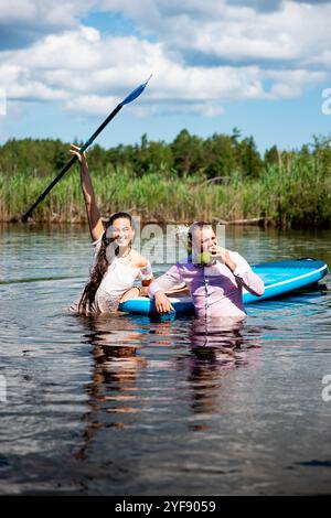 Bella donna e uomo sono caduti in acqua dopo aver remare con sup in estate Foto Stock