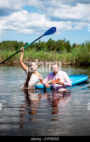 Bella donna e uomo che nuotano nel lago dopo aver canottato con sup in estate Foto Stock
