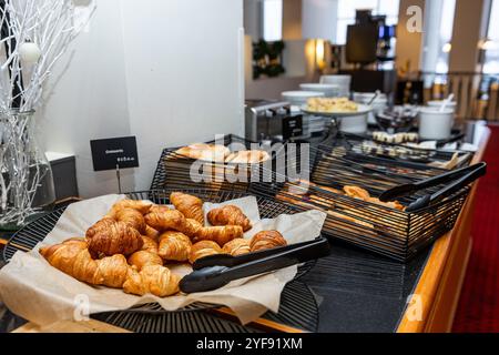 Selezione di croissant dorati e toast in cesti di filo nero sul bancone del buffet Foto Stock