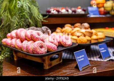 Deliziose ciambelle e muffin in in esposizione ad una colazione a buffet dolce in hotel Foto Stock