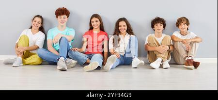 Ritratto di un bambino sorridente che guarda allegro alla fotocamera su sfondo grigio della parete Foto Stock