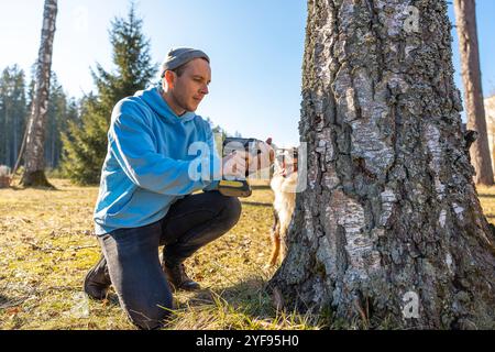 Uomo che sta perforando un albero di betulla per raccogliere linfa fresca in una brillante giornata primaverile Foto Stock