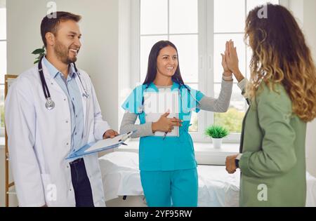 Felice amichevole sorridente infermiera e medico supporto e dare cinque alti al loro paziente Foto Stock