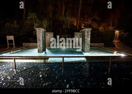 Rilassatevi in un lussuoso resort turistico con una piscina splendidamente illuminata, creando un ambiente tranquillo sotto le stelle di notte Foto Stock