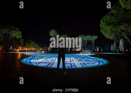 Rilassatevi in un lussuoso resort turistico con una piscina splendidamente illuminata, creando un ambiente tranquillo sotto le stelle di notte Foto Stock