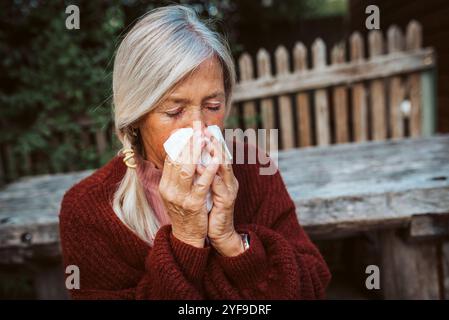 Le donne anziane si sentono male, soffiando il naso che cola e chiuso nel tessuto e starnuto. Foto Stock