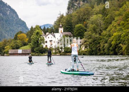 Una donna pagaia su una tavola da SUP in una calda giornata estiva, godendosi l'acqua rinfrescante e il clima soleggiato Foto Stock