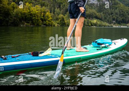 Uomo che pagaia in un lago alpino, che gode del paesaggio montano, gonfiabile SUP Board Adventure Foto Stock