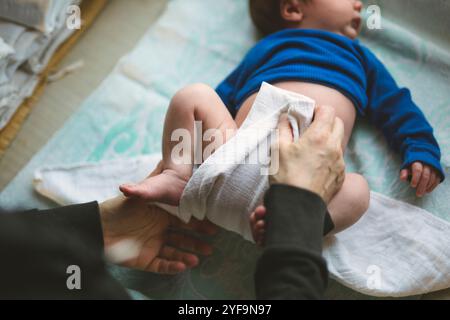 Direttamente sopra la vista della donna anziana che cambia pannolino del neonato sdraiato a casa Foto Stock