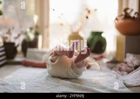 Bambino a piedi nudi disteso su una coperta a casa Foto Stock