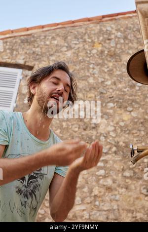 Vista ad angolo basso dell'uomo di mezza età che lava il viso con acqua Foto Stock