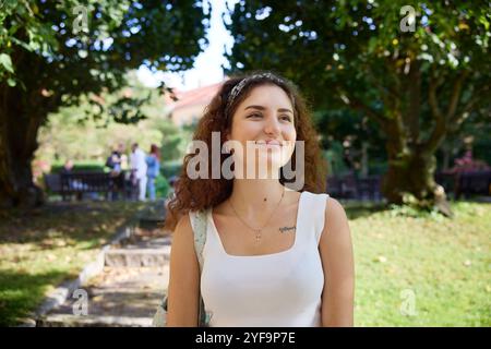 Sorridente giovane bella donna giorno che sogna al parco Foto Stock