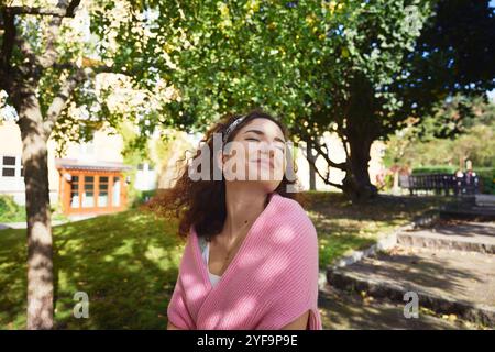 Giovane donna sorridente con maglione che trascorre del tempo libero al parco Foto Stock