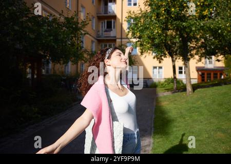 Giovane donna spensierata che balla con le braccia tese al parco Foto Stock