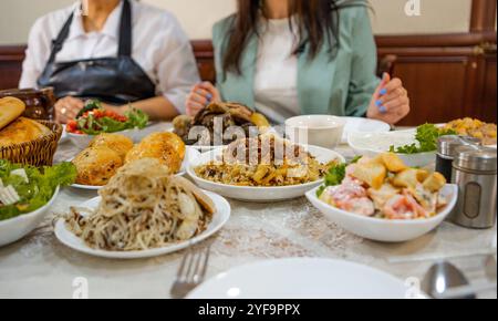 Assortimento di cibo uzbeko, pilaf, samsa, lagman, manta, cibo shurpa dell'asia centrale. Pilaf uzbeko fatto in casa o plov di agnello servito in utensili da cucina in ghisa Foto Stock