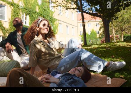 Gruppo di giovani amici che riposano sul campo erboso del parco Foto Stock