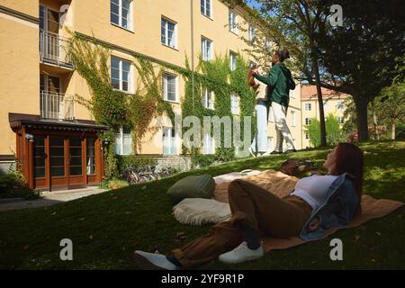 Giovane donna che guarda amici che ballano nel parco Foto Stock
