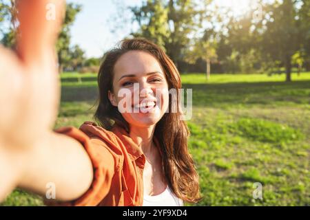 Una giovane ottimista si fa un selfie mentre cammina nel parco dopo il lavoro. Foto Stock