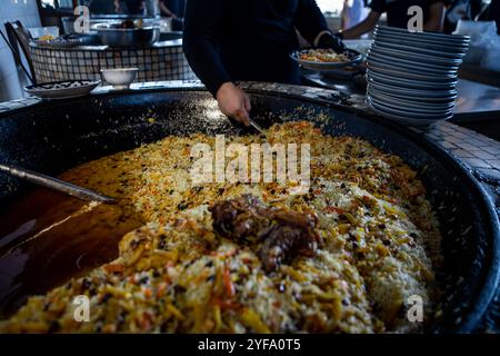 Vero pilaf uzbeko in un enorme calderone. Centro per pilaf a Tashkent. Cucina piatti nazionali in Uzbekistan. Foto Stock