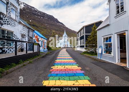 La famosa strada arcobaleno a Seydisfjordur con edifici islandesi intorno mostrano opere d'arte dipinte sulle pareti. Città di Seydisfjordur in Islanda. Foto Stock