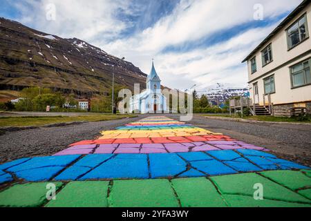 La famosa strada arcobaleno a Seydisfjordur con edifici islandesi intorno mostrano opere d'arte dipinte sulle pareti. Città di Seydisfjordur in Islanda. Foto Stock