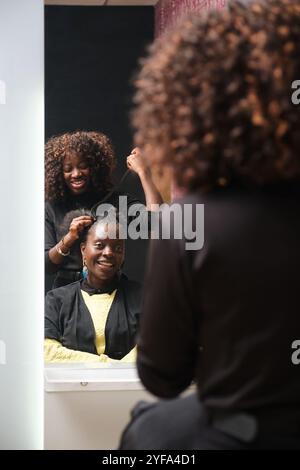Parrucchiere che realizza trecce a uncinetto per sorridere il cliente in salone Foto Stock