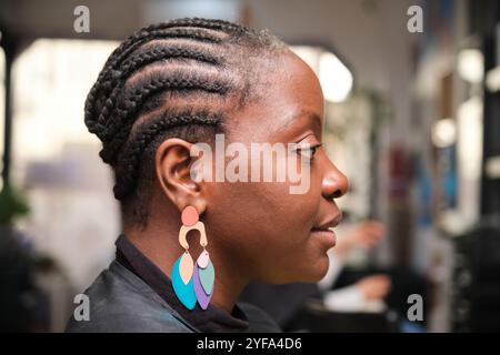 Parrucchiere che fa trecce all'uncinetto alla donna nera nel parrucchiere afro Foto Stock