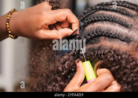 Parrucchiere che fa trecce all'uncinetto per acconciature nel parrucchiere afro Foto Stock