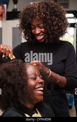 Parrucchiere che fa trecce all'uncinetto per un cliente felice in un parrucchiere Foto Stock