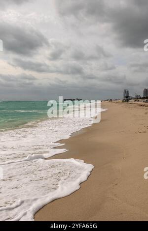 Onde schiumose che si lavano a terra sotto un cielo nuvoloso a Miami Beach Foto Stock