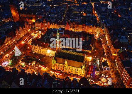 Vista aerea del mercato di Natale di notte con bancarelle illuminate, alberi festivi ed edifici storici a Breslavia, Polonia. Città europea decorata Foto Stock