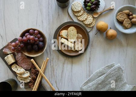 Tagliere di salumi con frutta, cracker, formaggio e noci su un tavolo Foto Stock